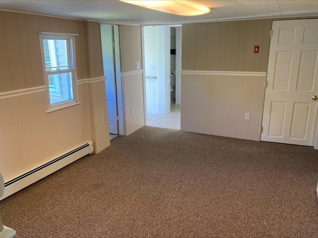 carpeted empty room featuring a baseboard heating unit