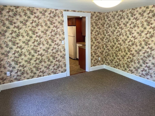 carpeted empty room with wallpapered walls and baseboards