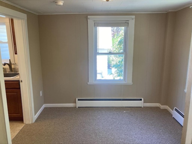empty room featuring a baseboard heating unit, light carpet, and a sink