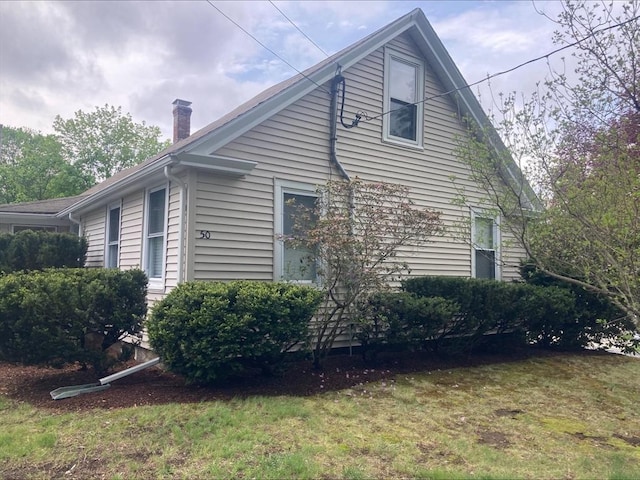view of home's exterior with a chimney and a yard
