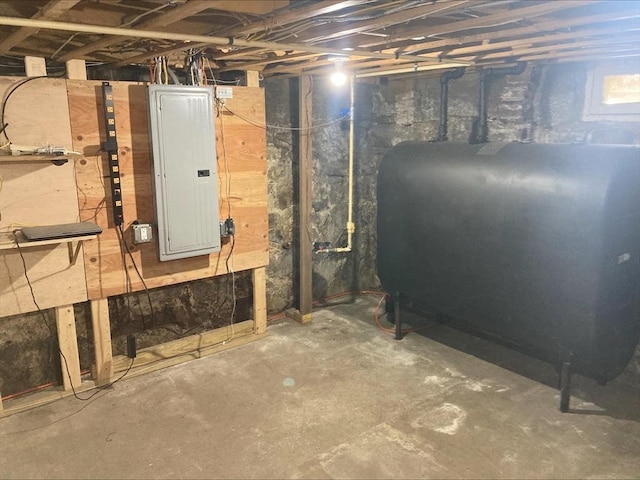 unfinished basement featuring electric panel and heating fuel