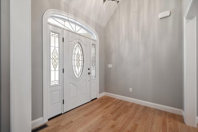 foyer entrance with light wood-type flooring and vaulted ceiling