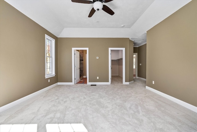 unfurnished bedroom featuring ceiling fan, connected bathroom, a walk in closet, a closet, and light colored carpet