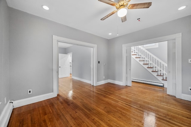 spare room with hardwood / wood-style flooring, ceiling fan, and a baseboard heating unit