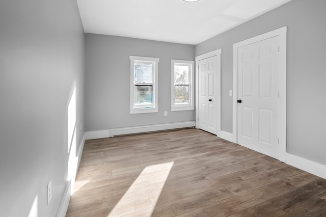 unfurnished bedroom featuring baseboard heating and light wood-type flooring