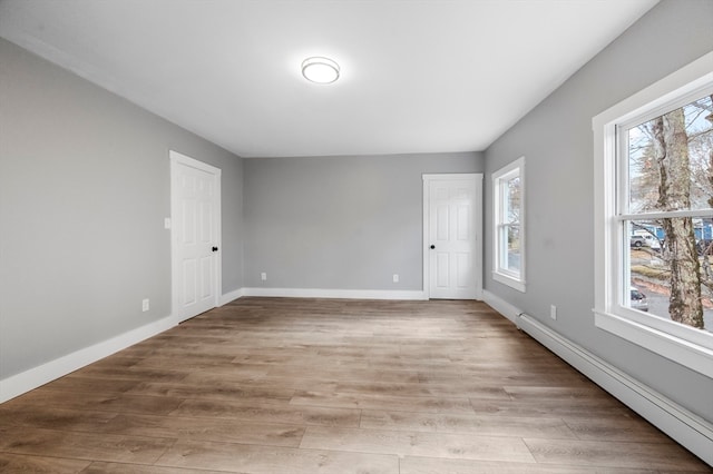 unfurnished room with a baseboard radiator and light hardwood / wood-style floors