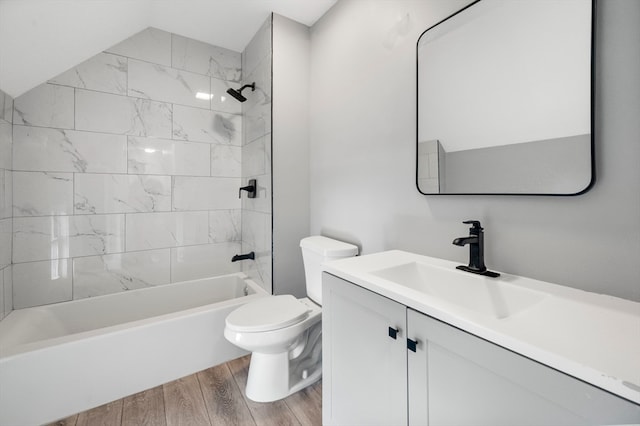 full bathroom with vanity, tiled shower / bath, vaulted ceiling, toilet, and wood-type flooring