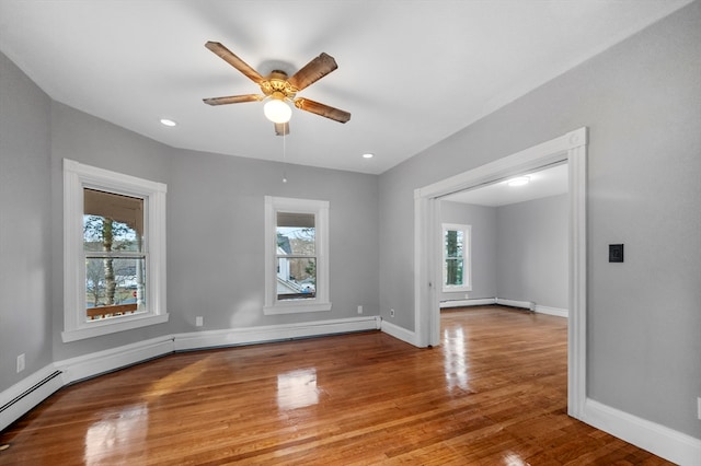 unfurnished room featuring hardwood / wood-style floors, ceiling fan, and baseboard heating