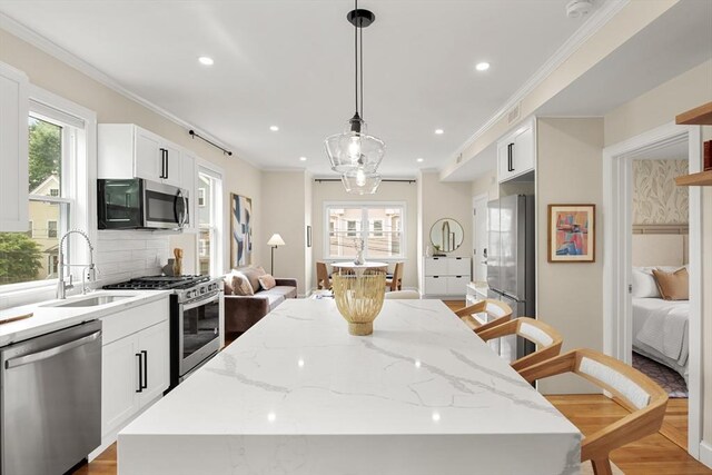 34 Leniston St Unit 2, Boston, MA 02131 - kitchen with appliances with stainless steel finishes, a sink, a center island, crown molding, and light stone counters