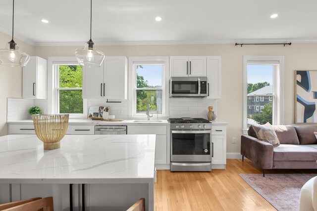 34 Leniston St Unit 2, Boston, MA 02131 - kitchen with appliances with stainless steel finishes, a sink, white cabinets, decorative backsplash, and light wood finished floors