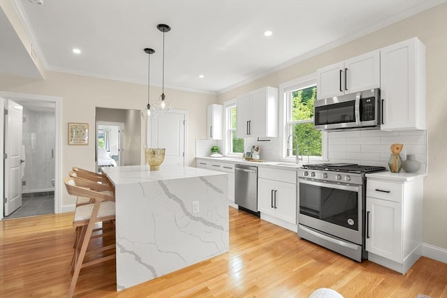 34 Leniston St Unit 2, Boston, MA 02131 - kitchen with appliances with stainless steel finishes, a sink, a center island, white cabinetry, and ornamental molding