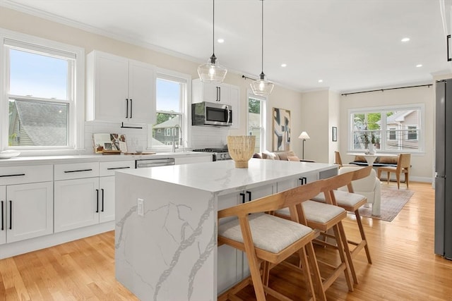 34 Leniston St Unit 2, Boston, MA 02131 - kitchen featuring stainless steel appliances, a center island, crown molding, decorative backsplash, and a kitchen breakfast bar