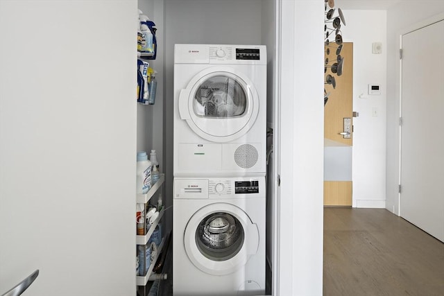 laundry room featuring hardwood / wood-style floors and stacked washer and clothes dryer