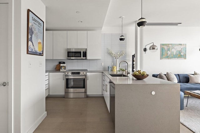 kitchen with sink, white cabinets, hanging light fixtures, kitchen peninsula, and stainless steel appliances