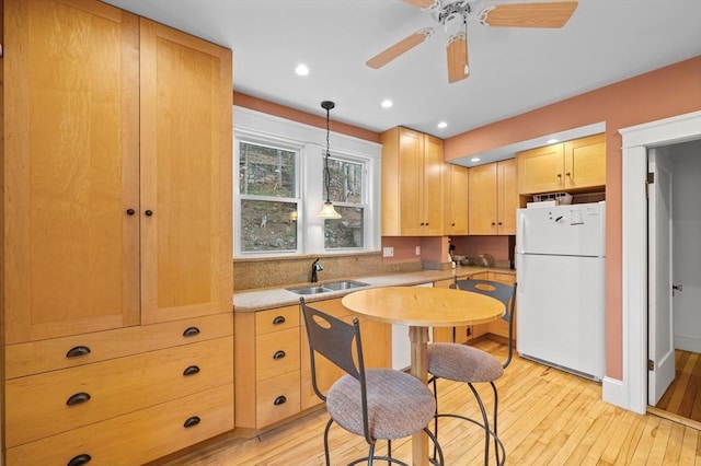 kitchen featuring a sink, light countertops, freestanding refrigerator, light wood-style floors, and light brown cabinets