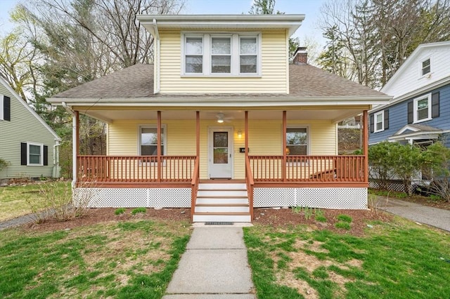 bungalow with a porch, a shingled roof, a front yard, and a chimney