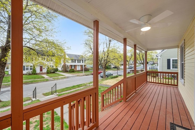 wooden deck featuring a porch, a ceiling fan, and a residential view
