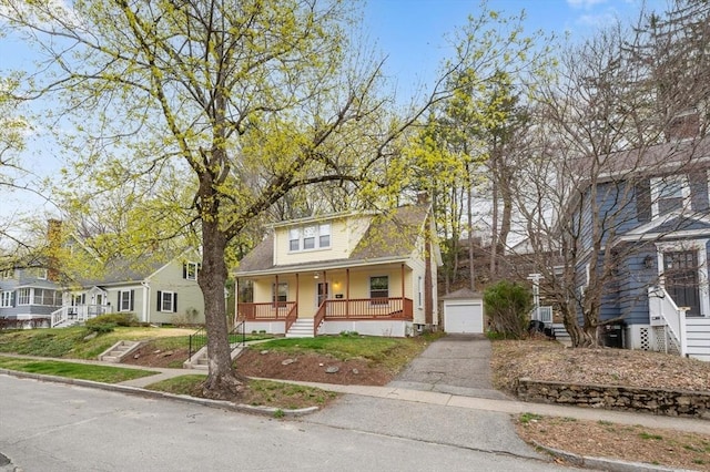 view of front of property featuring stairs, a detached garage, a porch, an outbuilding, and driveway