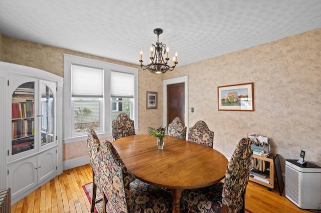 dining area with baseboards, light wood-style flooring, and a notable chandelier
