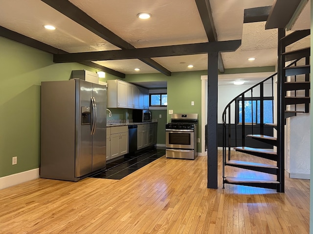 kitchen featuring white cabinets, light hardwood / wood-style floors, beam ceiling, and appliances with stainless steel finishes