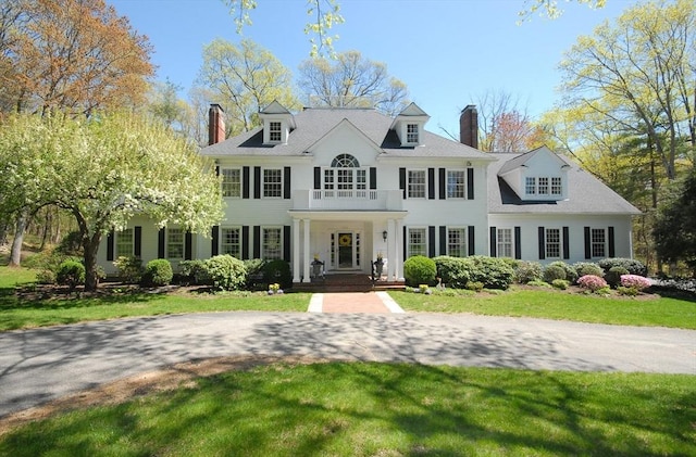 colonial house featuring a chimney and a front yard