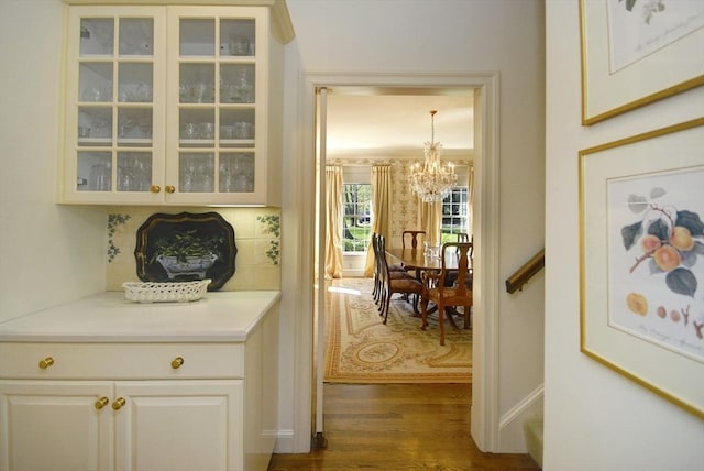 hallway featuring an inviting chandelier, baseboards, and dark wood-type flooring