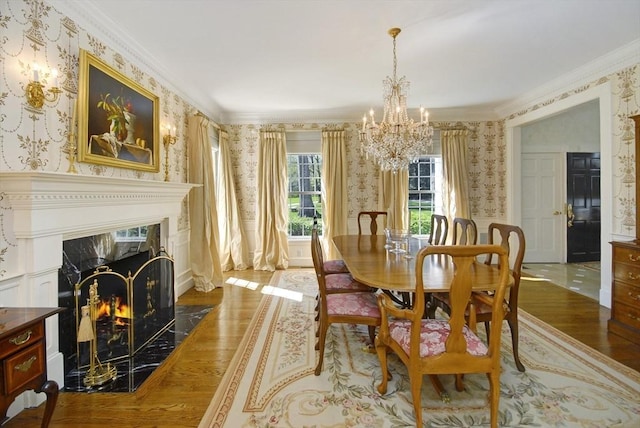 dining space with wallpapered walls, an inviting chandelier, wainscoting, crown molding, and wood finished floors