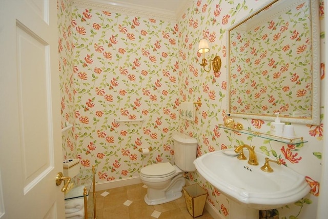 half bathroom with a sink, toilet, ornamental molding, baseboards, and wallpapered walls