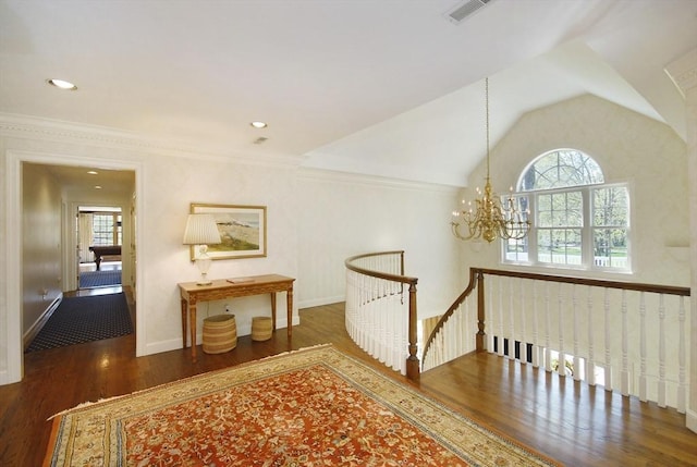 hallway featuring lofted ceiling, an inviting chandelier, visible vents, wood finished floors, and an upstairs landing