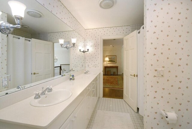 bathroom with tile patterned floors, wallpapered walls, a sink, and double vanity
