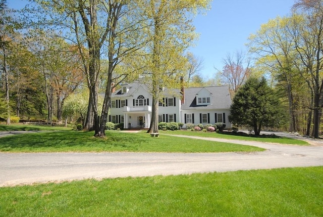 colonial-style house featuring a front lawn