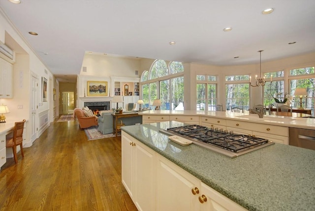 kitchen featuring recessed lighting, stainless steel gas stovetop, an inviting chandelier, wood finished floors, and a fireplace