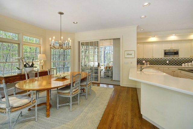 dining space featuring ornamental molding, recessed lighting, a notable chandelier, and wood finished floors