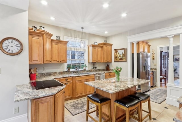 kitchen with a sink, appliances with stainless steel finishes, a breakfast bar, and decorative columns