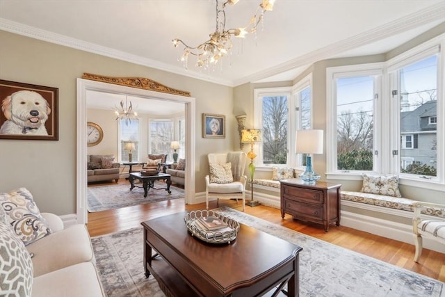 living room with crown molding, plenty of natural light, light wood-type flooring, and a chandelier