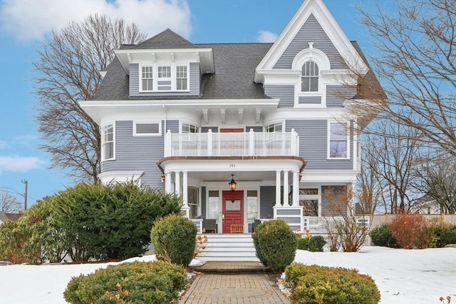 view of front facade featuring a balcony, a porch, and roof with shingles