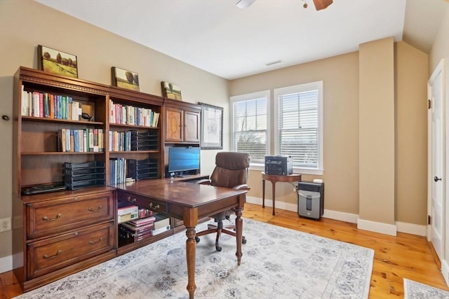 home office featuring visible vents, baseboards, light wood-type flooring, lofted ceiling, and a ceiling fan