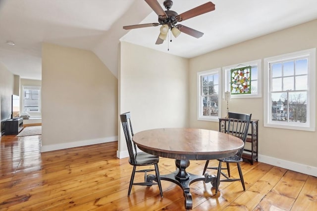 dining space with lofted ceiling, a ceiling fan, baseboards, and light wood finished floors