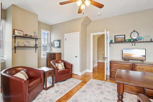 sitting room featuring a ceiling fan, light wood-type flooring, and baseboards