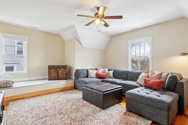 living room with visible vents, wood finished floors, baseboards, ceiling fan, and vaulted ceiling