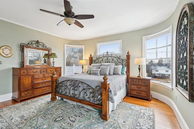 bedroom with a ceiling fan, wood finished floors, and baseboards