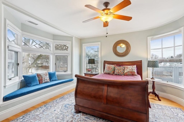 bedroom featuring ceiling fan, visible vents, baseboards, and wood finished floors