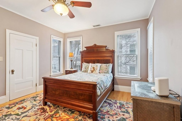 bedroom featuring baseboards, multiple windows, visible vents, and light wood finished floors