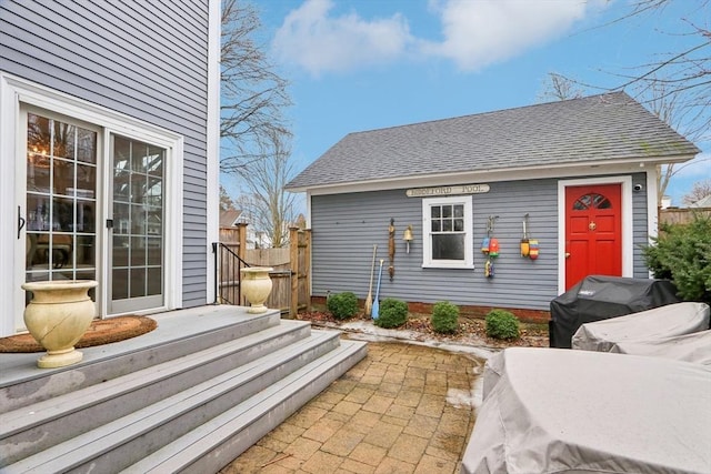 exterior space featuring fence and a shingled roof