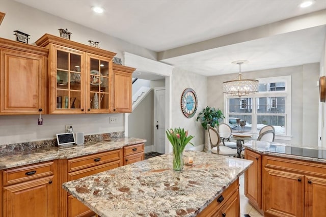 kitchen featuring glass insert cabinets, light stone countertops, and brown cabinetry