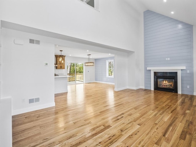 310 Old Westport, Dartmouth, MA 02747 - unfurnished living room featuring light wood finished floors, a towering ceiling, a glass covered fireplace, baseboards, and recessed lighting