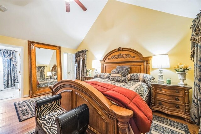 bedroom with ceiling fan, wood finished floors, and high vaulted ceiling