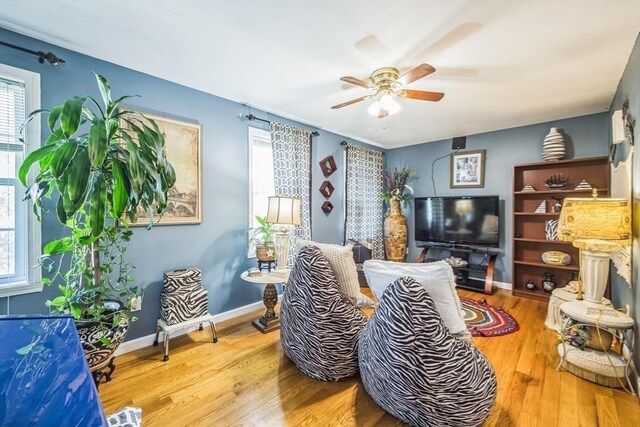 living room with baseboards, ceiling fan, and wood finished floors