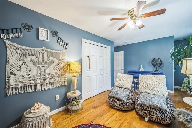 living area featuring baseboards, a ceiling fan, and wood finished floors