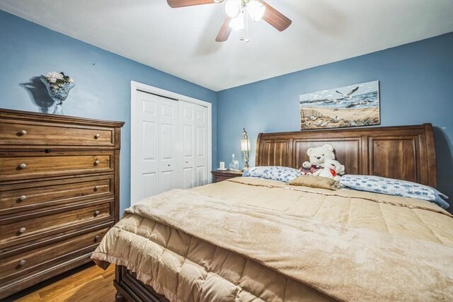 bedroom with ceiling fan, wood finished floors, and a closet